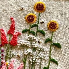 some flowers and bees are on a piece of fabric that has been stitched together