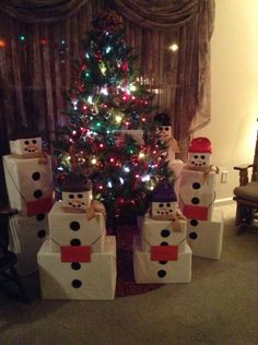 a christmas tree decorated with snowmen and presents in front of a small lite - up christmas tree