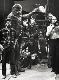 a group of people standing next to each other in front of a movie camera set