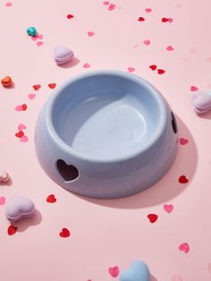 a blue bowl sitting on top of a pink table covered in confetti hearts