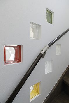 there are many different colored squares on the wall next to the stair rail and window