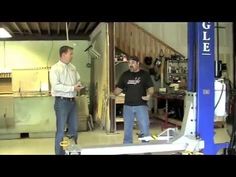 two men standing in a garage talking to each other