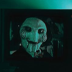 an old television with a creepy mask on it's face and the screen is turned green