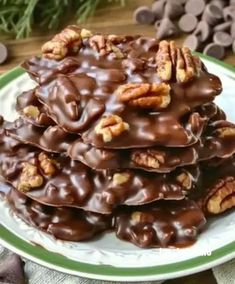 a pile of chocolate pecan cookies on a green and white plate next to nuts