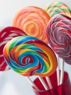 colorful lollipops are in a red vase