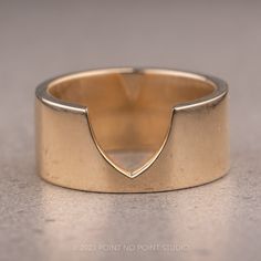 a close up of a gold ring on a gray surface with an arrow symbol in the middle