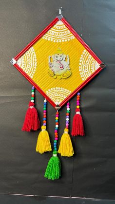 a yellow and red wall hanging with tassels