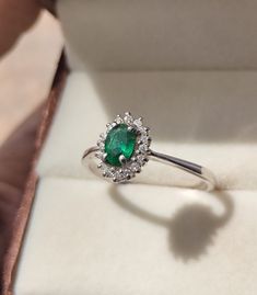 an emerald and diamond ring in a box