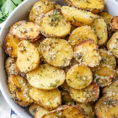 a white bowl filled with fried potatoes on top of a blue and white table cloth