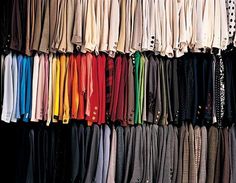 a rack full of different colored shirts and pants