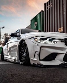 a white car parked in front of a shipping container