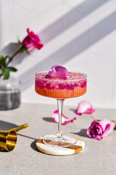 a pink drink sitting on top of a table next to flowers and other things in the background