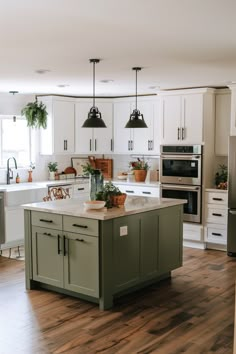 a kitchen with white cabinets and green island