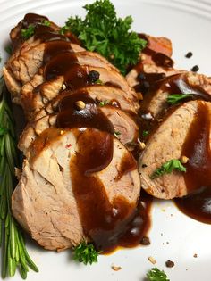 sliced pork with gravy and garnishes on a white platter