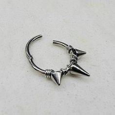 a silver ring with two spikes on it's end and an arrow charm hanging from the middle