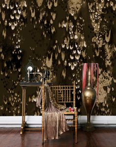 a chair and table in front of a wall with gold paint splattered on it