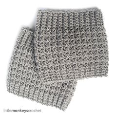 two gray knitted mittens sitting side by side on top of each other in front of a white background