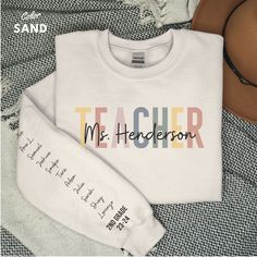 Give the ultimate thoughtful gift to your little one's teacher! This custom sweatshirt will be one she will hold close to her heart and will love to wear. The shirt is personalized with teacher's name and student's names along the left sleeve. As the number of students' names increases, the font size and spacing on the sleeve will be adjusted accordingly to accommodate all the names. * ABOUT THE SWEATSHIRT * Ideal for any situation, a unisex heavy blend crewneck sweatshirt is pure comfort. These Teacher Cricut Sweater, Personalized Teacher Shirts, Teacher Sweatshirt Ideas, Teacher Tshirt Ideas, Teacher Attire, Teacher Sweater, Aunt Sweatshirt, School Sweater, Education Shirts