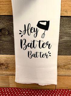 a tea towel with the words hey batter batter on it hanging from a wooden wall