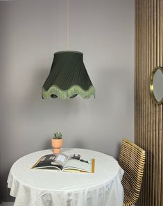 a table with a book on it and a lamp hanging from the ceiling over it