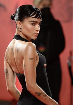 the back of a woman's body with tattoos on her left shoulder and right arm