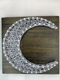 a string art moon on a wooden surface