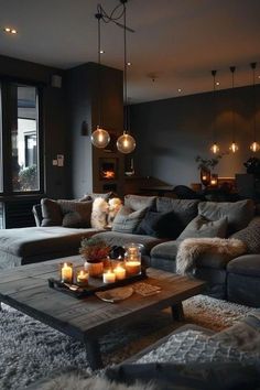 a living room filled with lots of furniture and candles on the coffee table in front of a large window