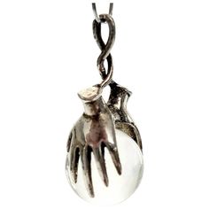 a silver pendant with an open hand on it's end and a ball in the middle