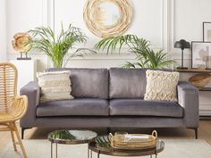 a living room filled with green couches and plants on top of them in front of a white wall