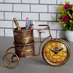 a golden clock sitting on top of a table next to a flower pot