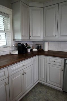 a kitchen with white cabinets and wood counter tops