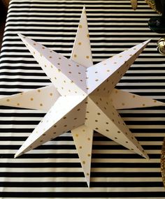 an origami star on a black and white striped tablecloth with gold polka dots