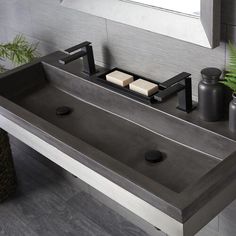 a bathroom sink with two soap dispensers on the top and a potted plant next to it