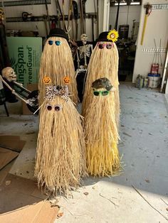 two scarecrows made out of straw with fake eyes and flowers on their heads