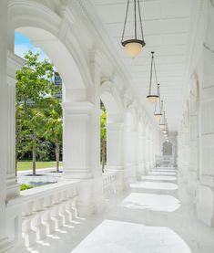 an empty white building with columns and chandeliers