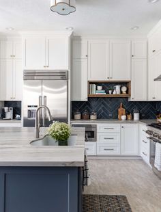 a kitchen with white cabinets and gray counter tops, an island in the middle is surrounded by blue accents