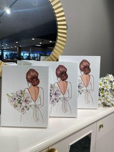 two cards with the bride's dress on them are sitting on a table in front of a mirror