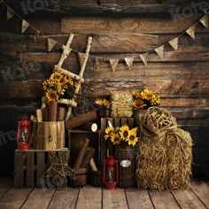 sunflowers and hay bales are arranged in front of a wooden wall