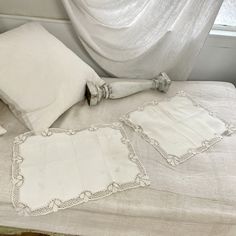 an old fashioned bed with white linens and decorative pillow cases on top of it