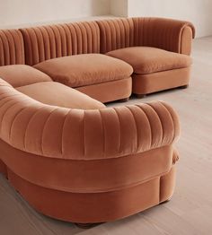 an orange curved couch sitting on top of a hard wood floor