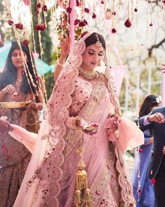 a woman in a pink bridal gown is walking down the aisle with other people