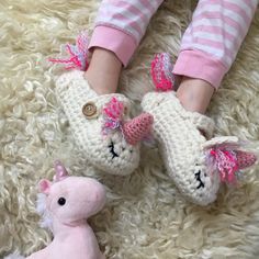 a child's feet wearing crocheted slippers and holding a stuffed animal