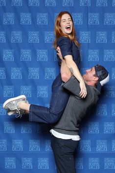 a man and woman standing on their backs in front of a blue backdrop