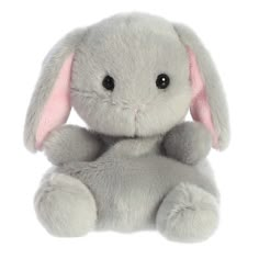 a gray stuffed rabbit sitting up against a white background