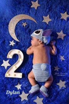 a baby laying on top of a blue blanket next to the number two in crochet