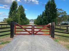 a wooden gate is open on a gravel road