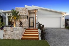 a modern home with stone and wood steps leading up to the front door, surrounded by greenery