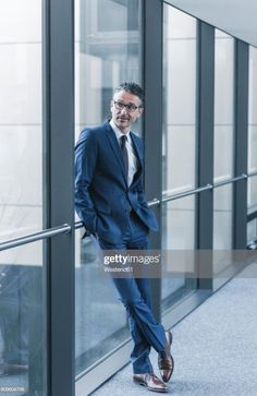 a man in a suit leaning against a glass wall