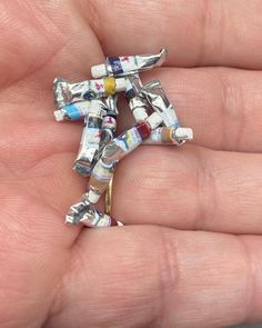 a person is holding a tiny cross made out of newspaper strips in their left hand