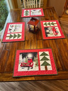 four quilted placemats sitting on top of a wooden table next to a lantern